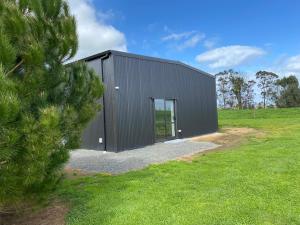 a black building in a field with a tree at Rural Guest Studio 