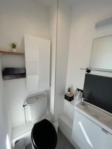 - une salle de bains blanche avec toilettes et siège noir dans l'établissement Le Studio M aux portes de Lille, à Marquette-lès-Lille