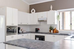 a kitchen with white cabinets and a granite counter top at Shells Narrawallee in Narrawallee