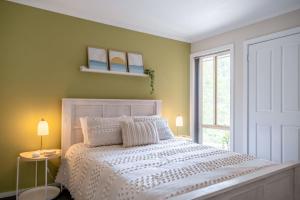 a bedroom with a white bed and a green wall at Shells Narrawallee in Narrawallee