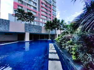 a swimming pool in front of a building with palm trees at Condotel at Sunshine100 Mandaluyong City near EDSA in Manila