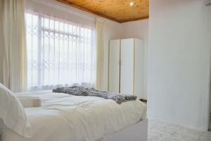 a bedroom with a bed and a large window at Lake Acres Guest House in Kokstad