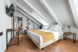 1 dormitorio con 1 cama, 2 mesas y TV en Hotel Viella, en Vielha