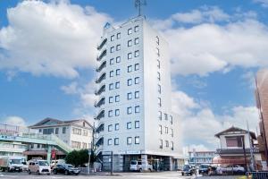 a tall white building with a clock on it at le Lac HOTEL KUSATSU in Kusatsu
