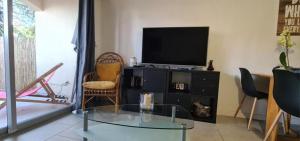 - un salon avec une télévision et une table en verre dans l'établissement Coquet Rez jardin plage parking wifi, à Saint-Mandrier-sur-Mer