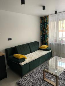 a green couch in a living room with yellow pillows at Apartament Żeromskiego2 in Biała Podlaska