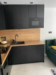 eine Küche mit schwarzen Schränken, einem Waschbecken und einem Sofa in der Unterkunft Apartament Żeromskiego2 in Biała Podlaska