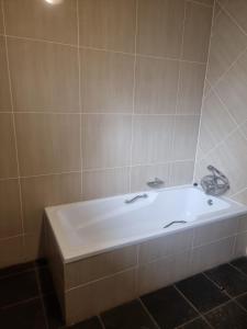 a white bath tub in a tiled bathroom at VMCC in Johannesburg