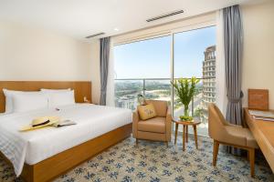 ダナンにあるLamanga Hotel & Suitesのベッド、デスク、窓が備わるホテルルームです。