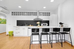 uma cozinha com armários brancos e bancos pretos em Ca L'oliera em Denia