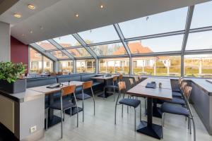 un restaurante con mesas, sillas y ventanas grandes en Corsendonk Duinse Polders en Blankenberge