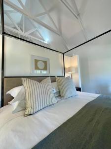 a bedroom with a large white bed with striped pillows at Mountain Cottages at Haskell Vineyard in Stellenbosch