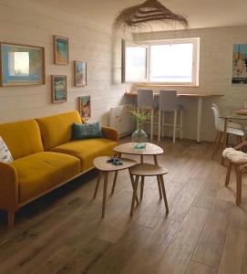 Una sala de estar con un sofá amarillo y una mesa. en Face à la mer, bel appartement, en Saint-Nazaire