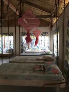 two beds in a room with two windows at Bohol Hammock Hostel in Batuan