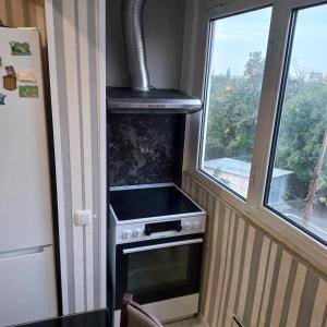 a kitchen with a stove and two windows at ПЕТРОВ 1 in Vratsa