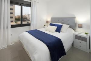 ein Schlafzimmer mit einem großen weißen Bett mit blauer Bettwäsche und einem Fenster in der Unterkunft Playamarinsa in Torre del Mar