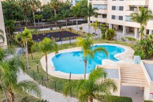 an overhead view of a pool with palm trees and a building at Playamarinsa in Torre del Mar