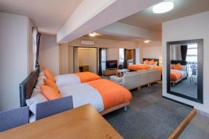 宮崎市にある宮崎マンゴーホテルのベッド2台とリビングルームが備わるホテルルームです。