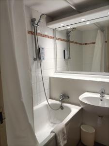 a bathroom with a sink and a tub and a mirror at Kyriad Genève St-Genis-Pouilly in Saint-Genis-Pouilly