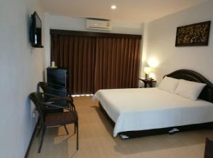 Habitación de hotel con cama y silla en Evergreen Resort Chanthaburi, en Chanthaburi
