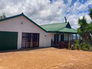 a white building with a green roof at Protea Wilds Retreat in Harkerville