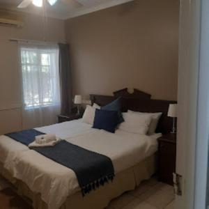 a bedroom with a large bed with blue and white pillows at Victorian Lodge in Bloemfontein