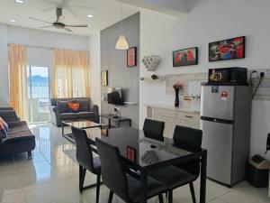 cocina y sala de estar con mesa y nevera en Simfoni Comfy 3BR Suite@Kuah Langkawi, en Kuah