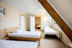 a attic room with two beds and a staircase at Corsendonk Duinse Polders in Blankenberge