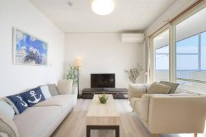 a living room with a couch and a tv at ライカムまで車で7分 オーシャンビュー付き 最大8人 駐車場2台 長期滞在にもおすすめ MK1 in Okinawa City