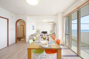 a dining room and living room with a table and chairs at ライカムまで車で7分 オーシャンビュー付き 最大8人 駐車場2台 長期滞在にもおすすめ MK1 in Okinawa City