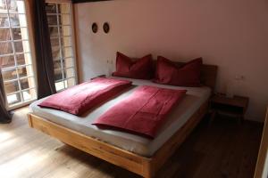 Un dormitorio con una cama con almohadas rojas. en Rommelehof, en Gutach