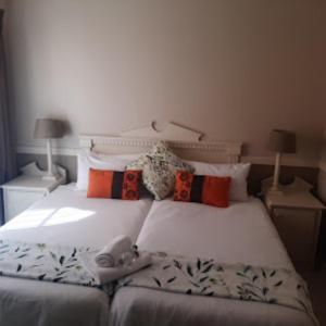 1 dormitorio con cama blanca y almohadas en Victorian Lodge en Bloemfontein