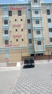 un coche aparcado frente a un gran edificio en برج ملاذ للشقق المخدومة بوادي بن هشبل en Bin Hashbal