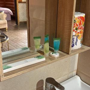 um espelho de casa de banho com três copos num balcão em الكوخ الريفي em Al Majmaah