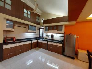 a large kitchen with wooden cabinets and a stainless steel refrigerator at 2BHK Modern Suites in North Goa in Saligao
