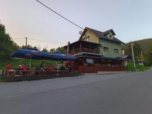 a group of people sitting at a restaurant with umbrellas at Apartments Poljanak Green House in Plitvička Jezera