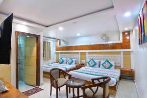 Habitación de hotel con 2 camas y mesa en Hotel Glow Inn Paharganj-3 Mins Walk From New Delhi Railway Station, en Nueva Delhi