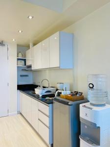 eine Küche mit weißen Schränken und blauen Geräten in der Unterkunft Sophisticated Oceanview Studio in La Mirada in Mactan