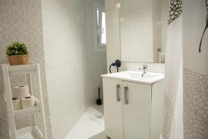 Baño blanco con lavabo y espejo en City town apartment, en Santander