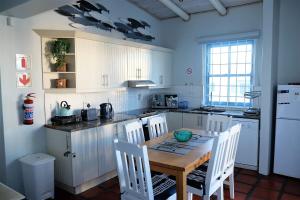 a kitchen with a wooden table and white cabinets at Beach Bliss in Paternoster
