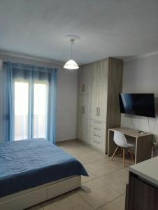 a bedroom with a bed and a desk and a television at Varkaris Room 1 in Katarráktis
