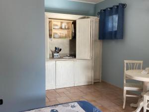 a kitchen with white cabinets and a blue curtain at Hotel Villa Del Parco in La Maddalena