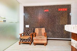 a room with two chairs and a wall at Collection O Blossom Suites in Bangalore