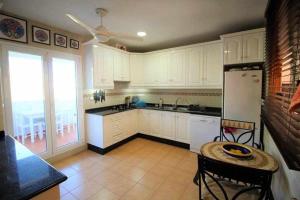 cocina con armarios blancos, mesa y ventana en Preciosa casa adosada con piscina privada, en Mojácar