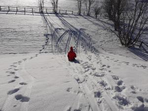 eine Person in einer roten Jacke, die im Schnee sitzt in der Unterkunft Résidence Les Clarines ( by Popinns ) in Les Rousses