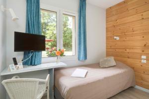 a bedroom with a bed and a desk and a window at Hôtel Acacia Nancy sud Lunéville in Lunéville