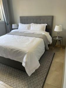 um quarto com uma cama grande com lençóis brancos e almofadas em 642 on Vincent em Pretoria