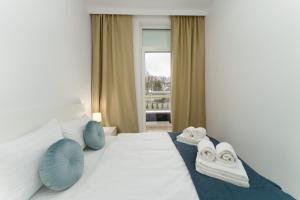 a bedroom with a white bed with blue pillows and a window at Apartament Przystań Ku Morzu by HolidaySun in Sianozety