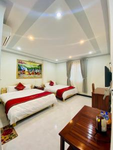 Habitación de hotel con 2 camas y mesa en Khách sạn Hưng Việt (Măng Đen) en Kon Tum