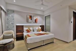 a bedroom with a king sized bed and a chair at Hotel Elements Surat in Surat